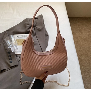 Détail d'un sac demi-lune rose poudré avec textures tressées et chaîne dorée