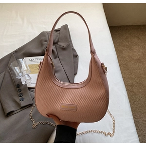 Détail du sac hobo rose avec texture tressée, logo métallique et chaîne dorée