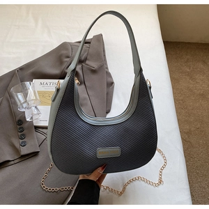 Détail du sac demi-lune gris avec surpiqûres en cuir et chaîne dorée