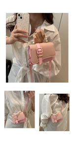 Detail of pink woven crossbody bag with pearl handle and golden buckle strap detail