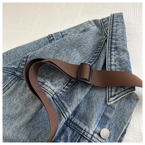 Dettaglio del tessuto denim blu chiaro con cinturino marrone e bottone argento cucito