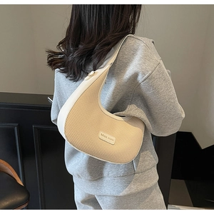 Gros plan du sac à main croissant en paille beige avec bordure en cuir blanc et étiquette