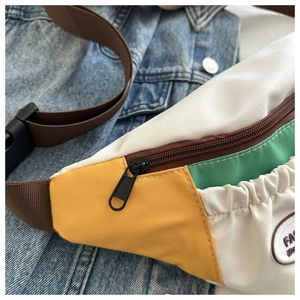 Dettaglio borsa da petto in nylon color-block con tracolla regolabile su denim