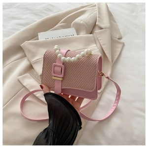 Detail of pink woven texture bag featuring elegant large faux pearl handle and strap