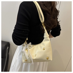 Close-up of creamy shoulder bag with cat claw charms and pearl lace bow detail