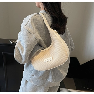 Détail du sac demi-lune tissé blanc cassé avec plaque logo Miss mini et bandoulière