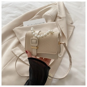 Detail of beige straw texture bag with elegant pearl handle and leather strap
