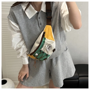 Détail du sac de poitrine en toile bicolore avec sangle réglable et détail d'étiquette