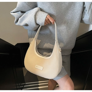 Détail du sac bandoulière demi-lune tissé beige avec lanière en cuir et étiquette Miss Mimi