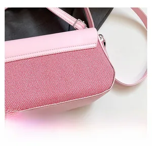 Detailed close-up of pink leather shoulder bag featuring red and white woven fabric texture
