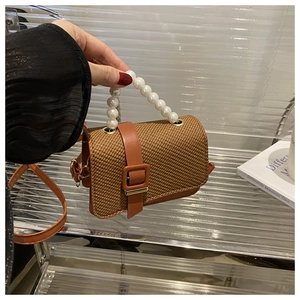 Detailed view of brown straw handbag with faux pearl handle and PU leather buckle strap
