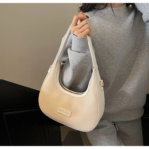 Détail du sac demi-lune tissé crème avec étiquette en cuir Miss mini et bandoulière