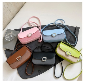Flat lay of multiple cross-body bags in five colors with woven fabric and D-buckle detail