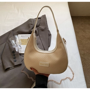 Détail du sac beige tissé avec chaîne dorée et finitions en similicuir crème