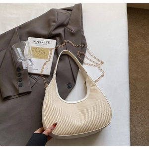 Gros plan du sac beige tissé en forme de demi-lune avec chaîne dorée chic