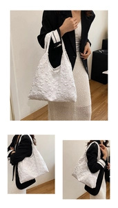 Dettaglio di una borsa tote bianca con rilievo floreale e morbida trama a bolle