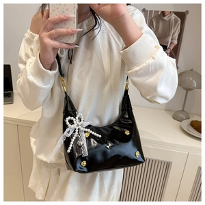 Detail of black glossy Hobo bag with pearl bow and lace trim in lifestyle setting