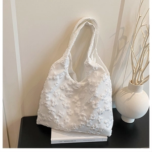 Macro shot of white floral embossed fabric on a tote bag with minimalist strap
