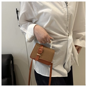 Brown woven texture crossbody bag with pearl handle and leather strap on model