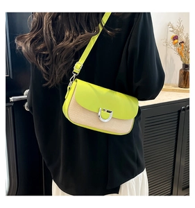 Detail of lime green flap crossbody bag with straw texture and silver D-ring buckle