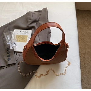 Détail d'un sac hobo demi-lune en cuir marron et paille tressée avec bandoulière chaîne