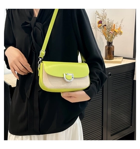 Detail of green leather flap and beige woven texture on a stylish crossbody bag
