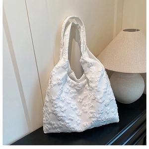 Detail of white tote bag featuring 3D embossed butterfly texture and lace floral pattern