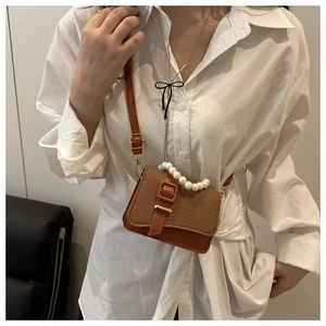 Detail of vintage straw mini bag with pearl handle and brown leather strap on model