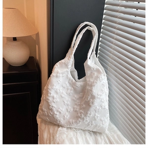 Detailed close-up of white tote bag with 3D butterfly embossed texture and floral lace style