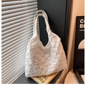 Detailed macro view of white lace tote bag with textured floral ribbon embroidery