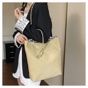 Detail of canvas tote bag with colorful beaded strap and black-white checkered lining