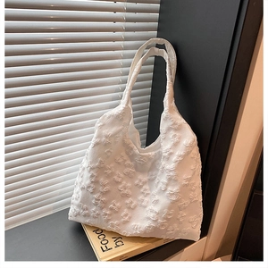 Detail of white tote bag featuring 3D butterfly embossed texture and dual handles