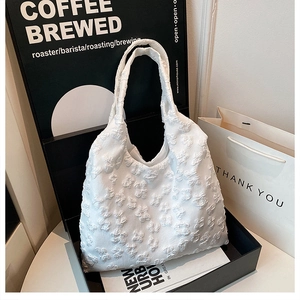 Macro shot of 3D popcorn textured white tote bag with embossed floral pattern details