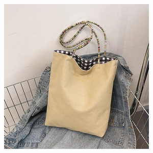 Detail of canvas tote bag with colorful beaded rope handle and checkered lining