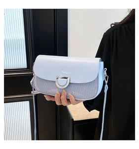 Detail of light blue crossbody bag featuring silver D-buckle and striped fabric trim