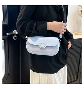 Detail of light blue crossbody bag with silver D-buckle and mixed fabric texture shown on model