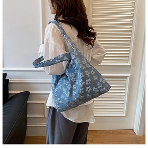 Close-up of a light blue tote bag with floral jacquard texture worn by a model