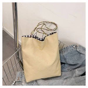 Close-up of beige canvas tote bag with black and white checkered lining and rainbow strap