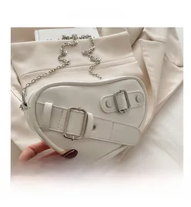 Detail shot of heart-shaped white faux leather crossbody bag with silver chain strap