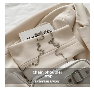 Detail of cream leather handbag featuring polished silver chain strap and buckle closure