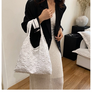 Detail of white tote bag featuring 3D floral jacquard texture and embossed lace fabric