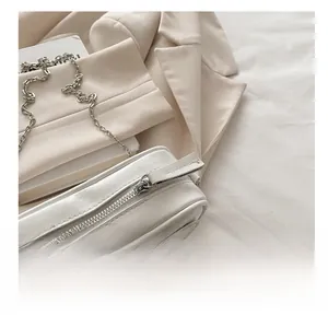 Close-up of a white leather crossbody bag showing the smooth silver metal zipper detail