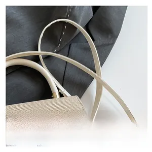 Close-up of woven straw texture and gold metal buckle on a cream crossbody bag