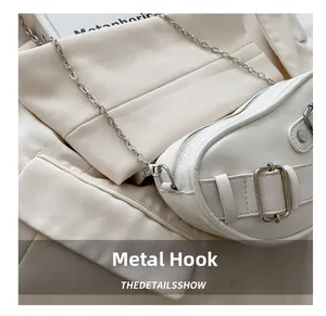 Detail of metal hook and silver chain strap on white leather saddle bag for women