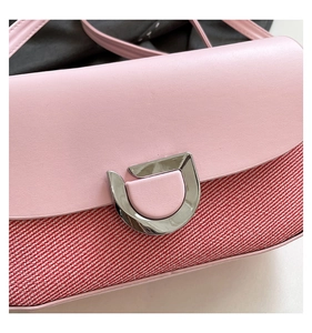 Detailed close-up of pink leather flap bag with silver U-shaped lock and woven texture