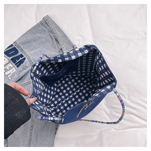 Detail of blue denim tote bag interior showing blue-white checkered lining and inner pocket