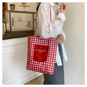Detail of red checkered canvas tote bag with front pocket and woven straps