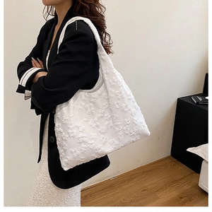 Detail of white floral lace tote bag showing the 3D texture and shoulder strap fit