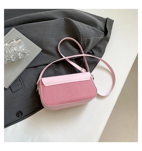 Detail of pink crossbody bag with red and white woven flap on grey blazer backdrop