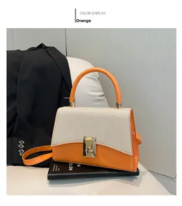 Detail of orange handbag featuring straw texture flap and golden twist lock closure